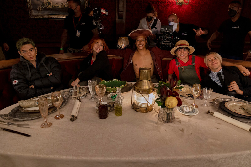 Mackenyu as Roronoa Zoro, Emily Rudd as Nami, Jacob Romero as Usopp, Iñaki Godoy as Monkey D. Luffy, and Taz Skylar as Sanji sit together in a booth in a restaurant in season 1 of 'One Piece.'