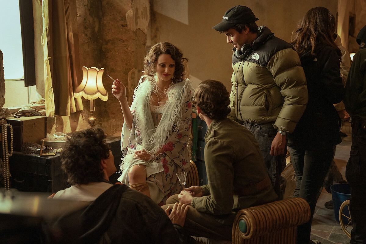 A behind the scenes photograph of Penélope Cruz as Nené in La Bola Negra while she is on set with directors Javier Ambrossi and Javier Calvo and her scene partner Guitarricadelafuente.