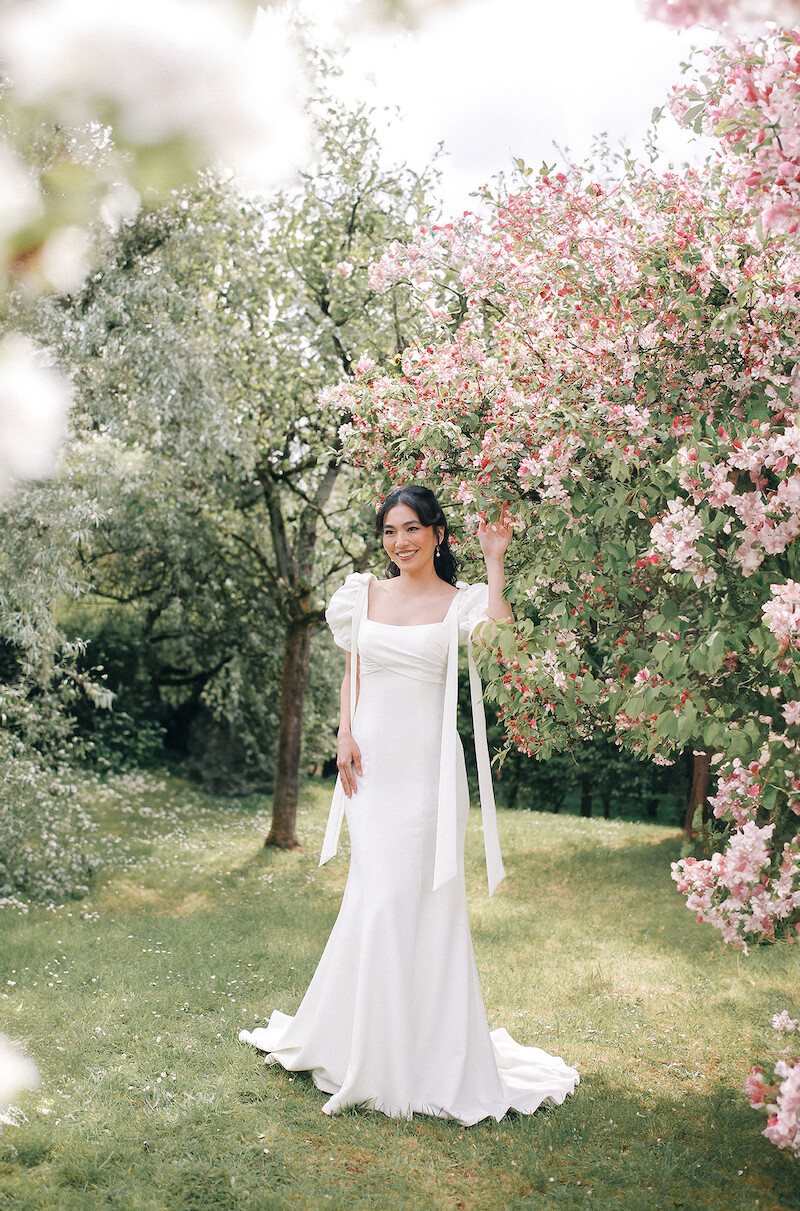 Woman in bridal dresses poses and looks off into the distance.