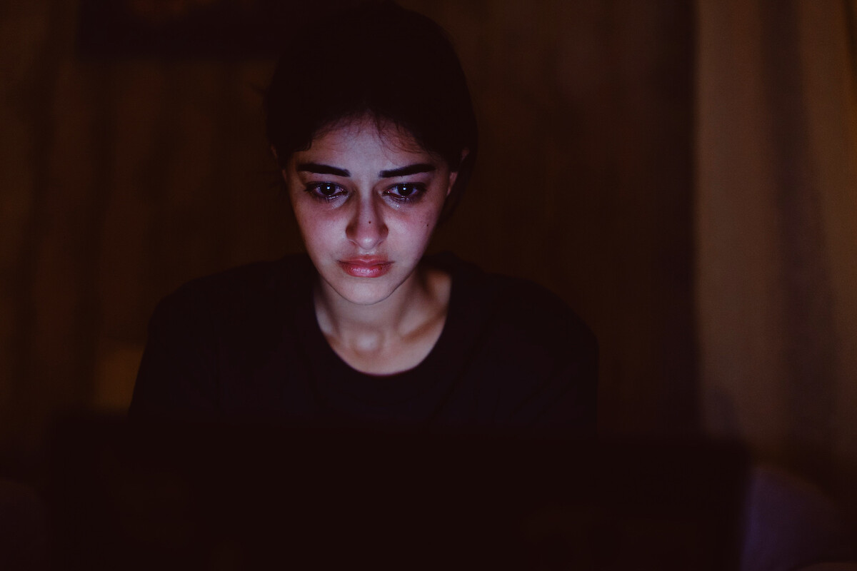Ananya Panday as Nella Awasthi is lit up by the glow of her laptop in a dark room in an image from the movie ‘CTRL.’