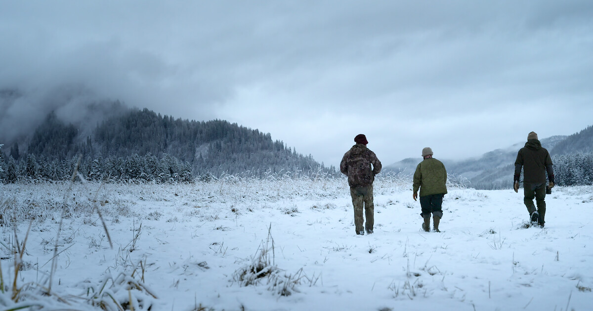 three people walking on a snowy field