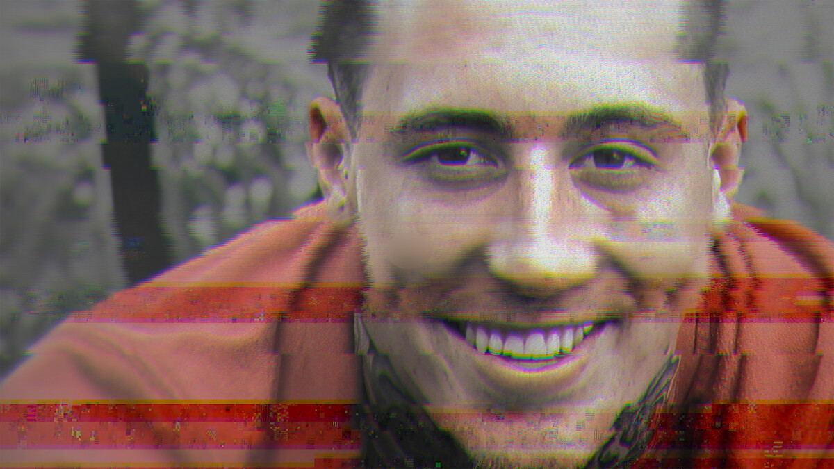 A man with a tattoo on his neck smiles at the camera outdoors. The image has digital distortion, glitch effects, and horizontal color lines, giving it a retro or corrupted video appearance.