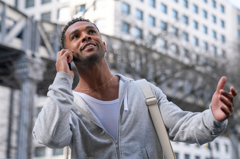 Lucien Laviscount as Alfie takes a phone call outdoors in Season 4 of 'Emily in Paris'