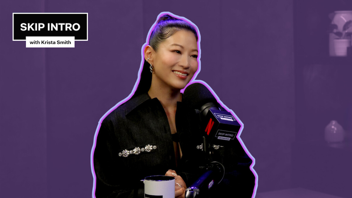 Arden Cho behind a podcast mic on a purple background