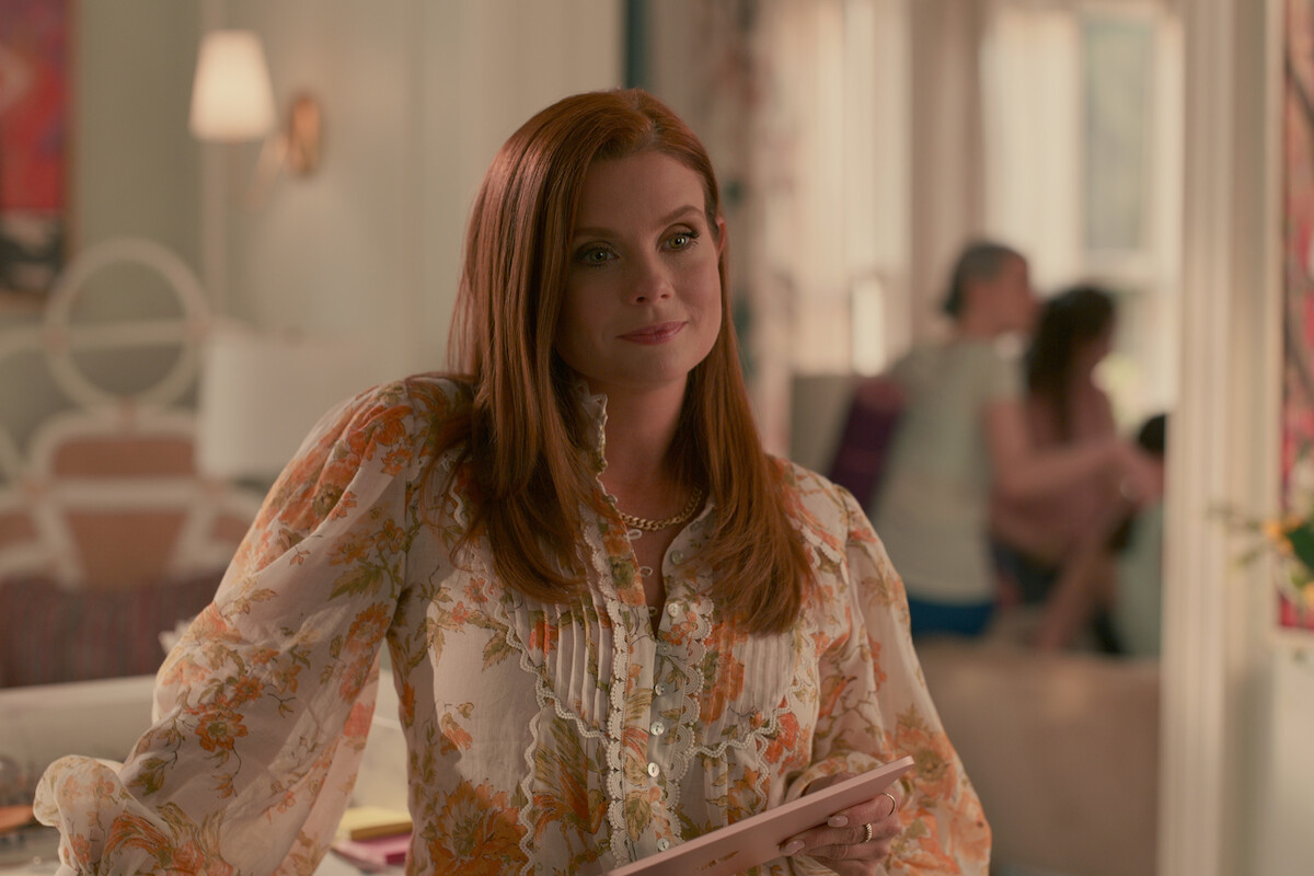 JoAnna Garcia Swisher, as Maddie Townsend, smiles wearing an orange and white blouse in Season 3 of ‘Sweet Magnolias.’
