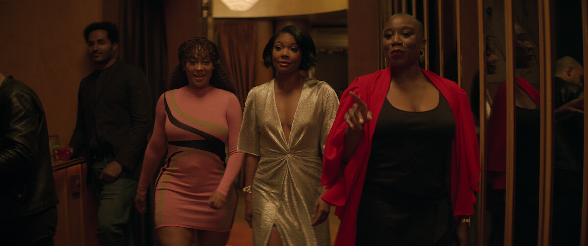 La La Anthony, Gabrielle Union and Aisha Hinds walk side-by-side into a bar wearing pink, silver and black dresses respectively in a still from ‘The Perfect Find.’