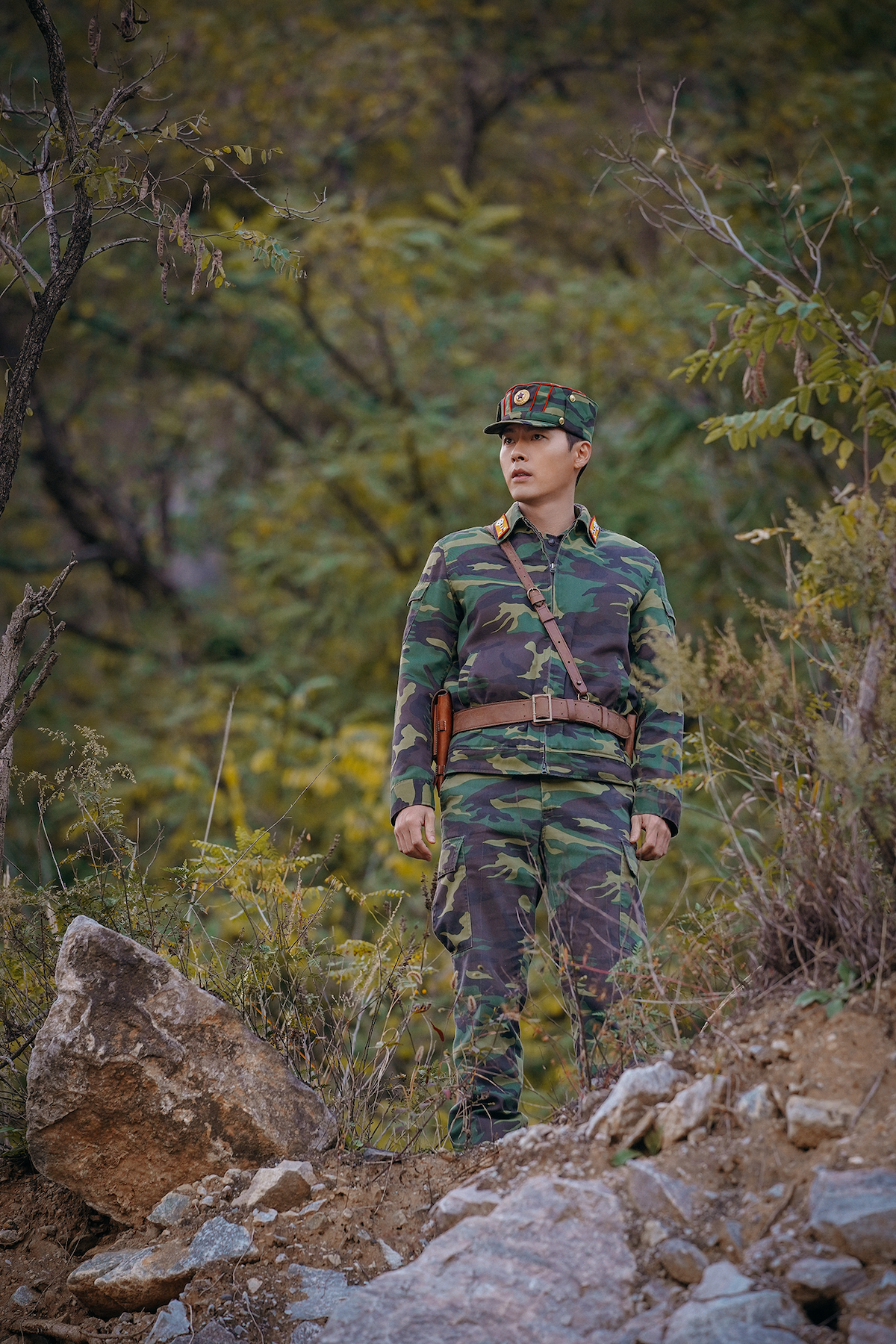 Homem com traje militar observa uma área de floresta