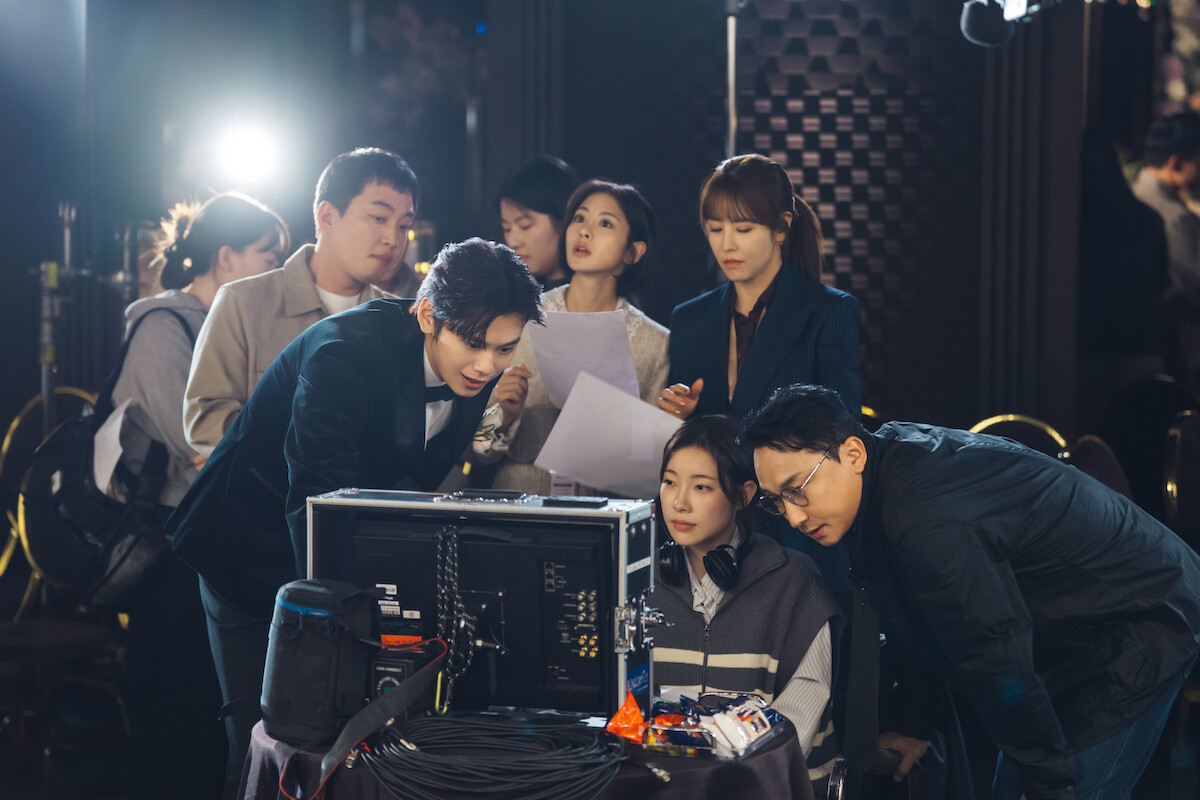 Grupo de pessoas se reúne em volta de um computador no set de filmagem