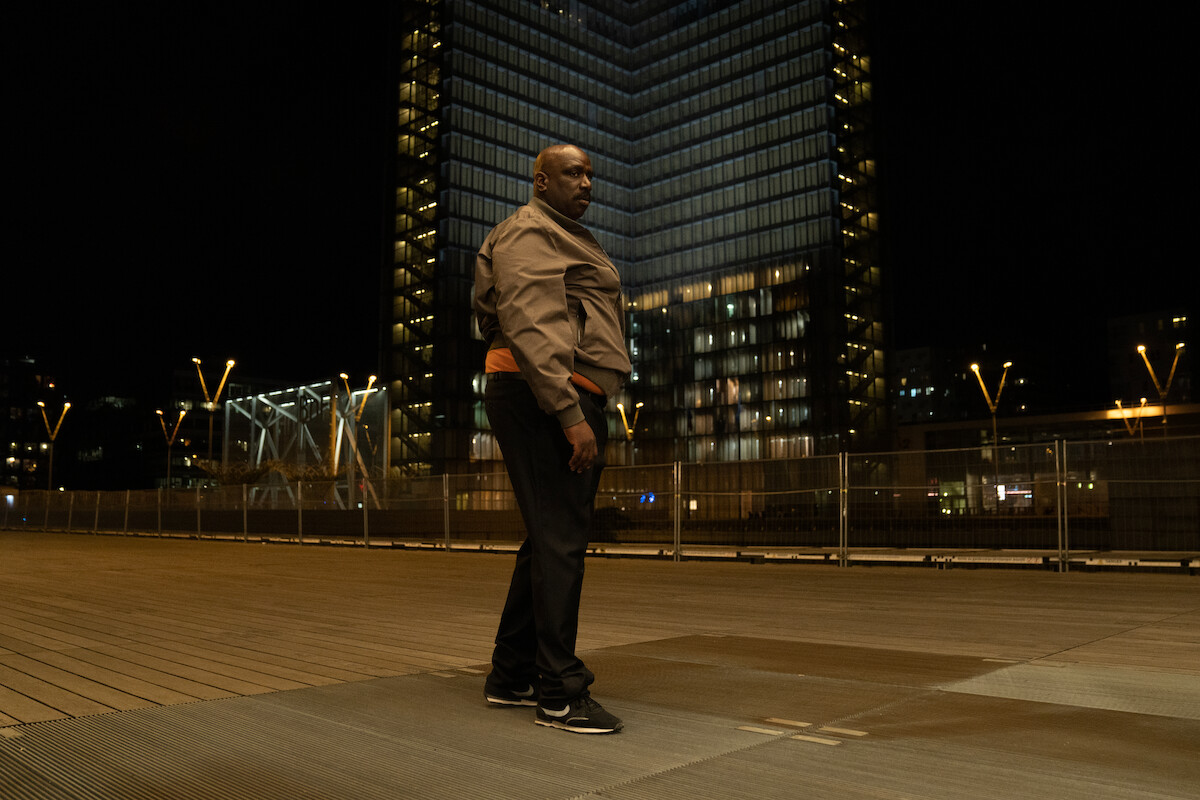 Steve Tientcheu as Jean-Luc Keller (2021) stands on a street in Season 3 of ‘Lupin.’