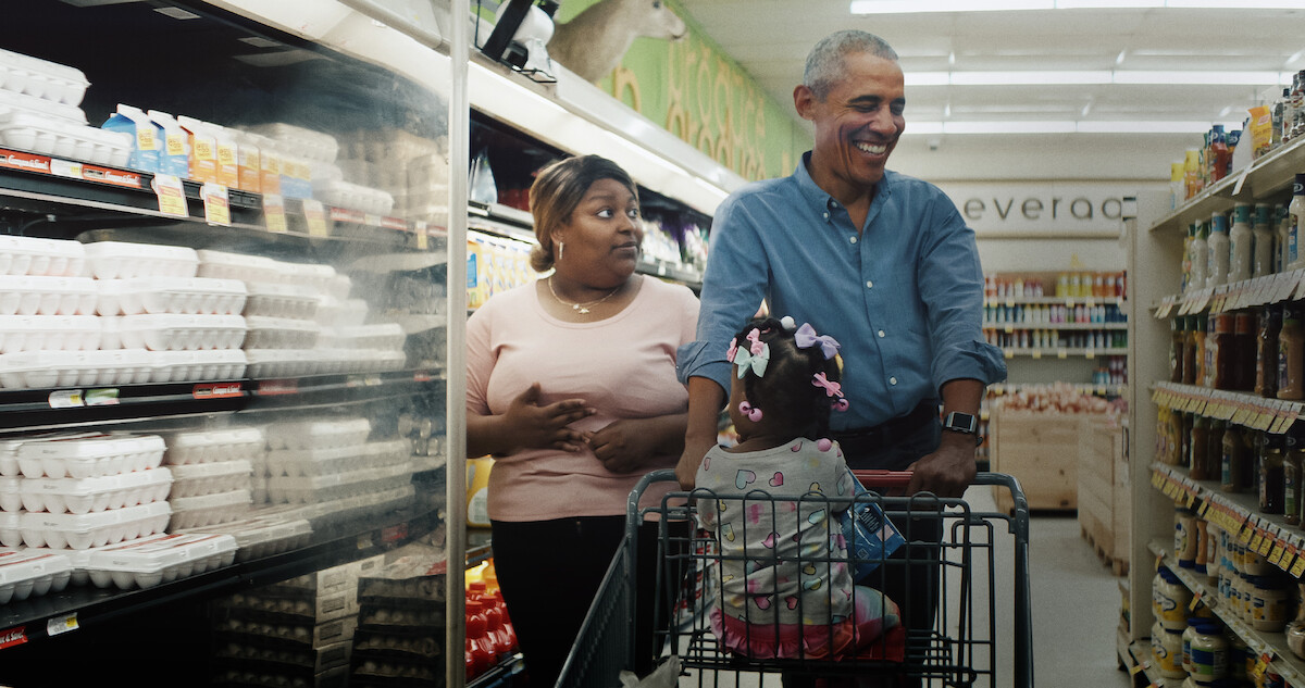 Barack Obama walks with a worker in a grocery store. 
