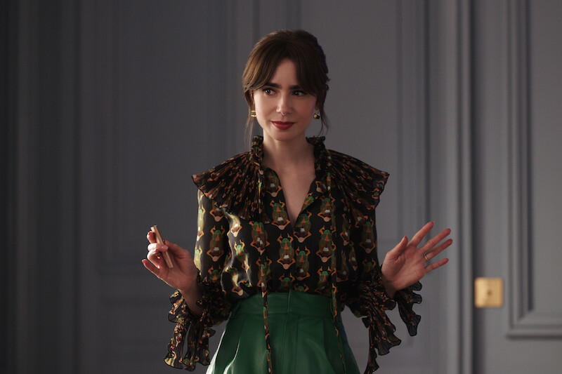 Lily Collins as Emily wears green pants and a dark blouse in Season 4 of 'Emily in Paris'