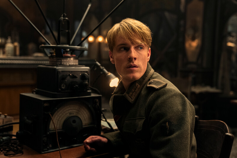 Louis Hofmann as 16 Year Old Werner sitting in front of a radio while wearing a uniform. 