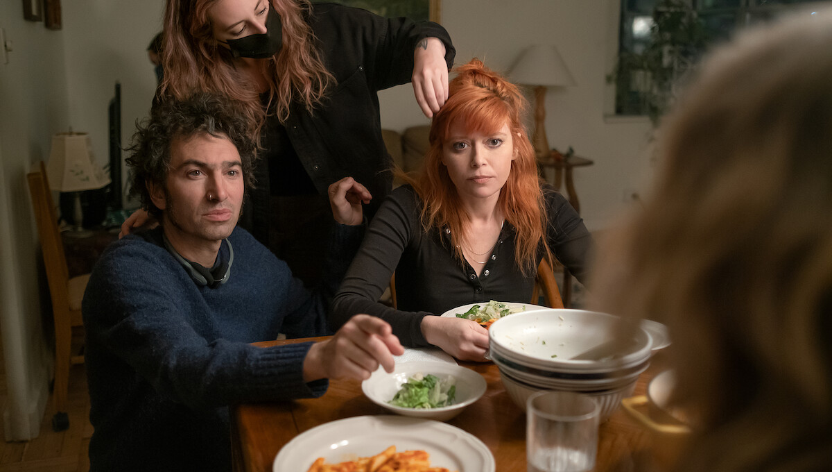 Azazel Jacobs sits in a brown-toned living room with Natasha Lyonne, who stretches back on a couch in a sweatsuit and points at Jacobs.