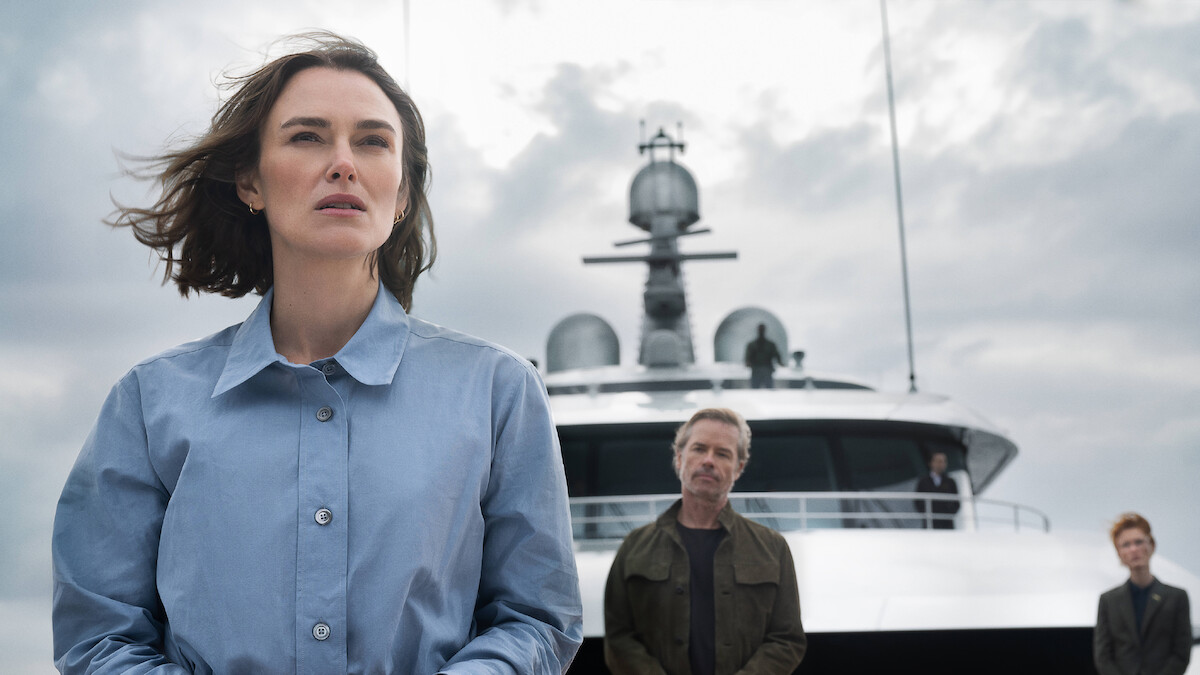 Kiera Knightly looks off into the distance with Guy Pearce watching her from behind.