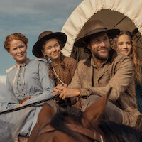 A pioneer family in old-fashioned clothing sits together on a covered wagon, smiling outdoors under a clear sky, suggesting a journey or migration in a rural historical setting.
