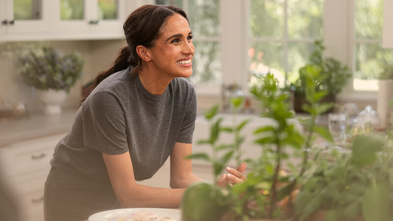 Meghan smiling in the kitchen with plants in the foreground.