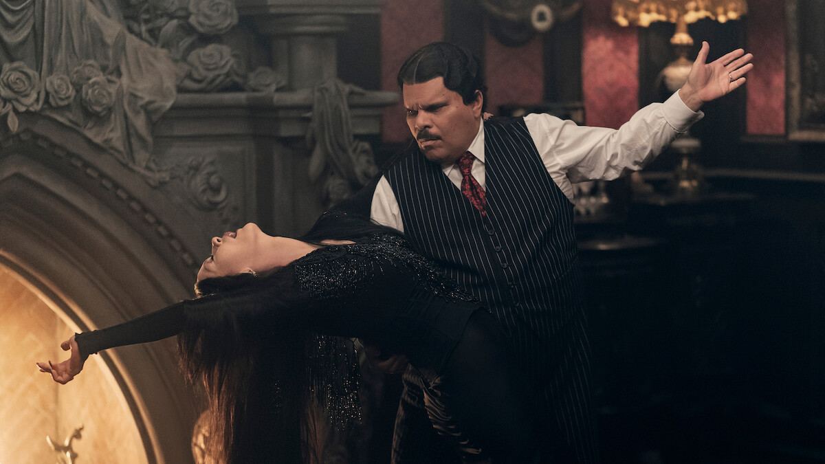 Catherine Zeta-Jones, como Mortícia Addams, e Luis Guzmán, como Gomez Addams, dançam juntos em frente a uma lareira na temporada 2 de ‘Wandinha’.