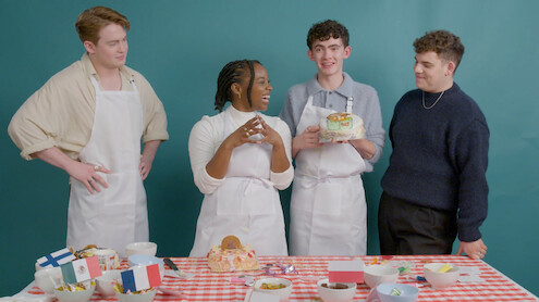Kit Connor, Corinna Brown, Joe Locke, and Tobie Donovan smile while decorating cakes 