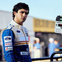 Ayrton Senna (Gabriel Leone) wears a white and blue racing suit behind the scenes of Senna.