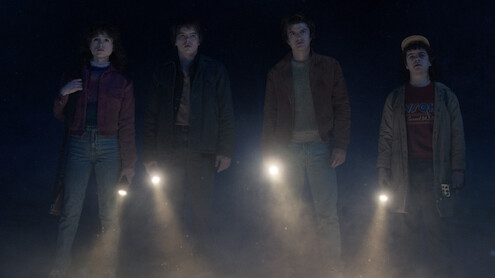 Natalia Dyer as Nancy Wheeler, Charlie Heaton as Jonathan Byers and Joe Keery as Steve Harrington, standing in the dark with flashlights pointed forward in 'Stranger Things 5.'