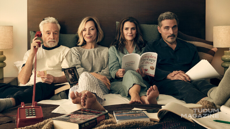 Keri Russell, Rufus Sewell, Allison Janney e Bradley Whitford deitados juntos em uma cama, usando pijamas.