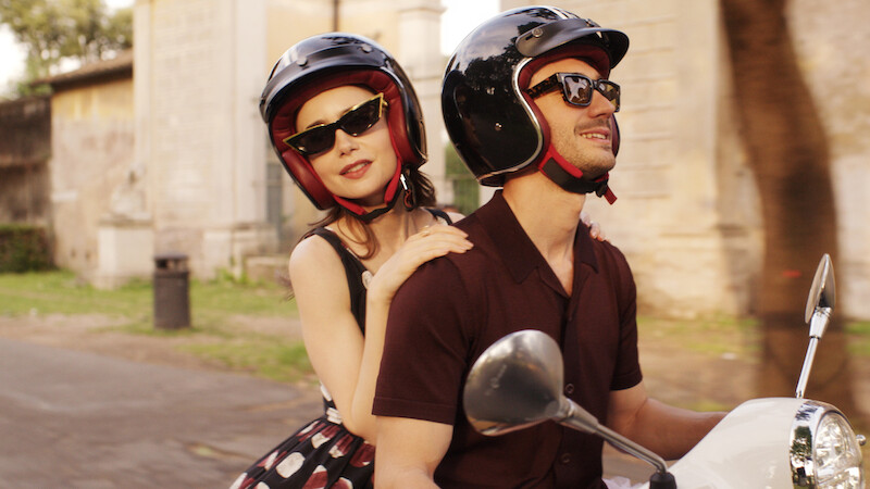 Lily Collins as Emily rides on the back of a motorcycle in Season 4 of 'Emily in Paris'