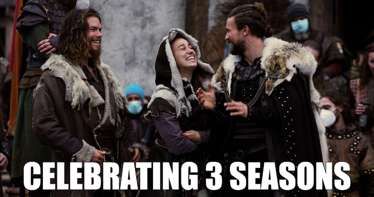 Sam Corlett, Lujza Richter and Leo Suter standing together, laughing on set.