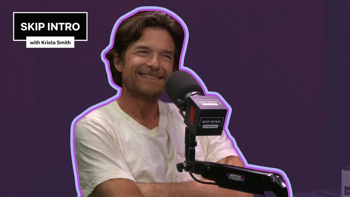 Jason Bateman smiles while speaking into a microphone on the 'Skip Intro with Krista Smith' podcast.