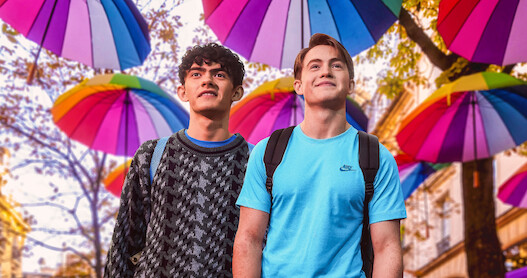 Joe Locke as Charlie and Kit Connor as Nick walk through the streets of Paris with umbrellas hanging above them in Season 2 of 'Heartstopper."
