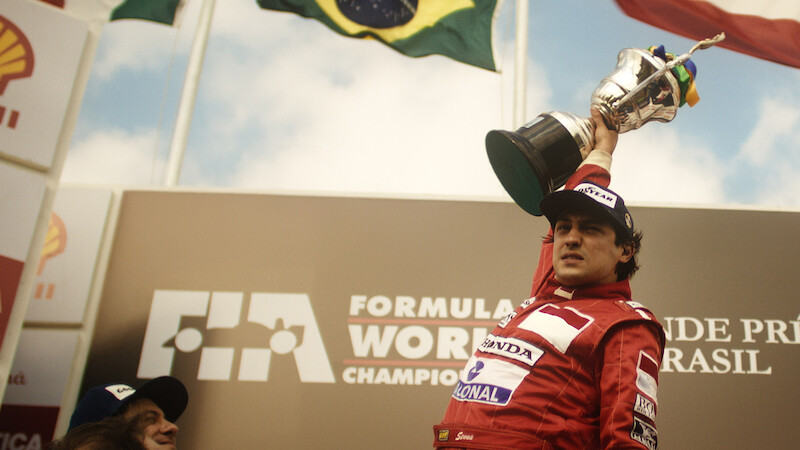 Gabriel Leone as Ayrton Senna lifts a large trophy in 'Senna'