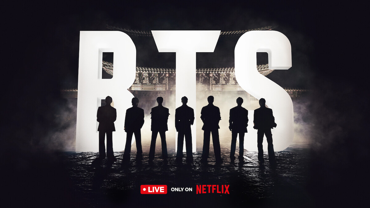 BTS standing silhouetted against giant 'BTS' letters