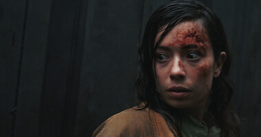 A woman looking frightened; she has a cut on her forehead