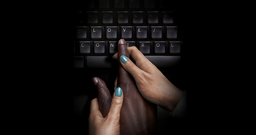Hands guiding a hand to type on a keyboard.