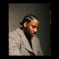 Malcolm Washington wears a patterned coat and sits in profile.