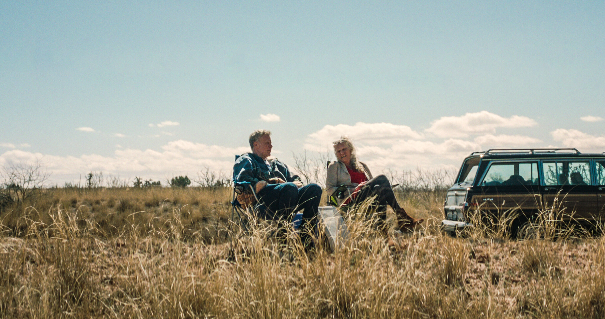 Will & Harper key art featuring Will Ferrel and harper steele sitting in lawn chairs in a field. 