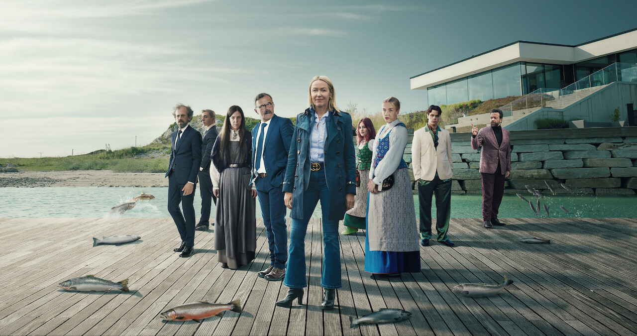 The cast of the series 'Billionaire Island' stand on a dock that's dotted with large fish.