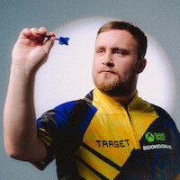 A focused man in a yellow and blue sports shirt holding a dart, preparing to throw, with a neutral indoor background and spotlight effect.