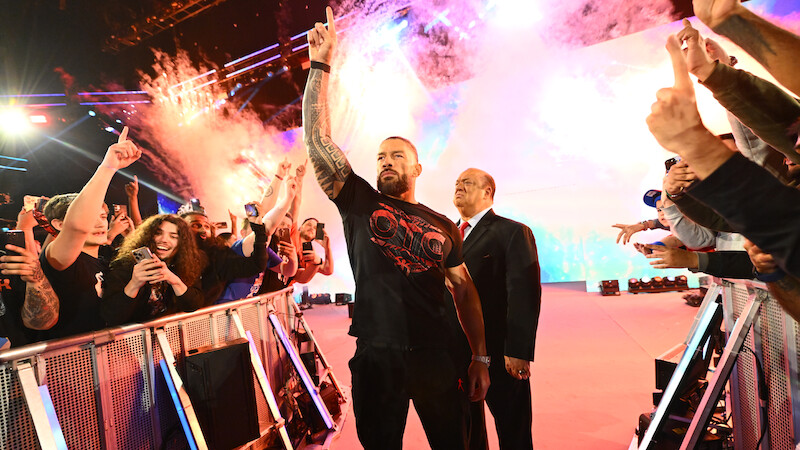 Roman Reigns enters greeting the crowd with pyrotechnics going off behind him.