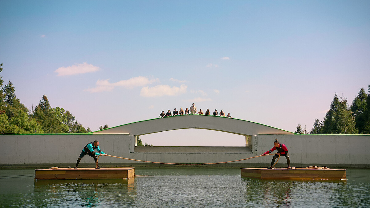 Players compete in a tug of war challenge on the water in 'Battle Camp'