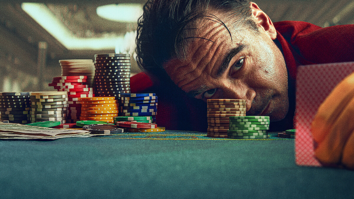 Colin Farrell as Lord Doyle laying his head on a poker table surrounded by chips.