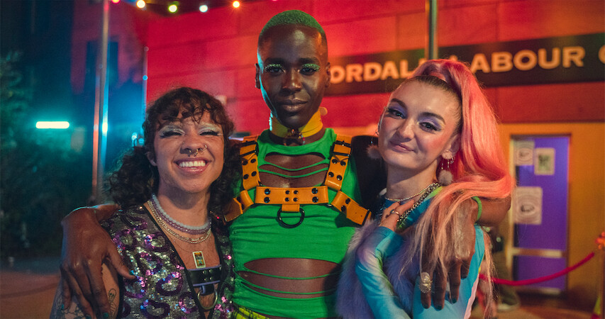 Felix Mufti as Roman, Ncuti Gatwa as Eric, and Anthony Lexa as Abbi stand together at a club in Season 4 of 'Sex Education.'