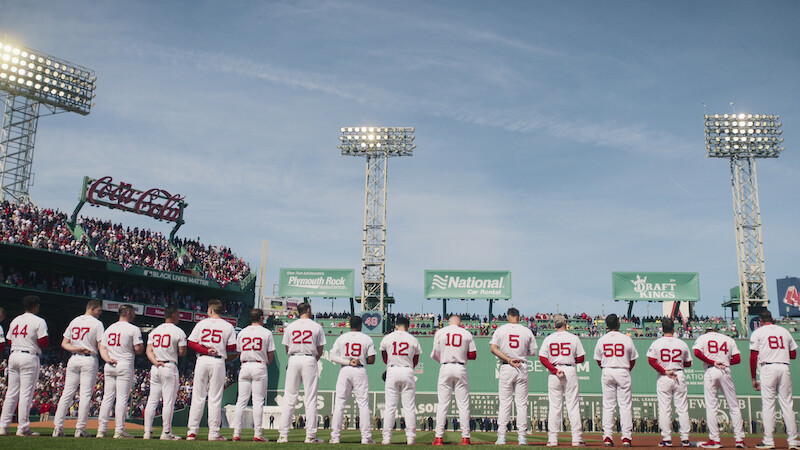 Boston Red Sox players lined up for the national anthem facing The Green Monster at Fenway Park