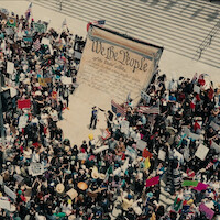 A shot from above of a crowd of political protestors on the steps of a government building.