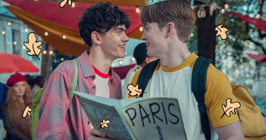 Joe Locke as Charlie and Kit Connor as Nick smiling together on the streets of Paris in Season 2 of Heartstopper. 
