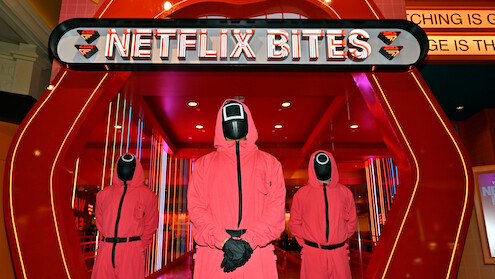 Three masked men from 'Squid Game' stand in front of the entrance to Netflix Bites Las Vegas at the MGM Grand