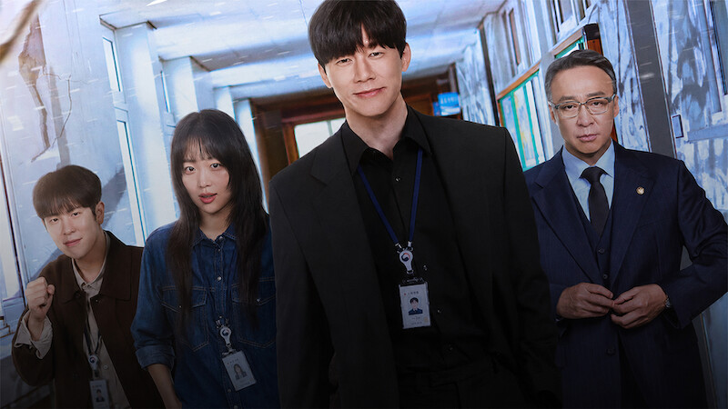 Four people wearing work ID badges stand in a well-lit hallway, dressed in business and casual attire, suggesting an office or professional environment.