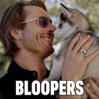Glen Powell (Gary Johnson) smiles at a Siberian Husky puppy he's holding. The word "Bloopers" is written in block letters in front.