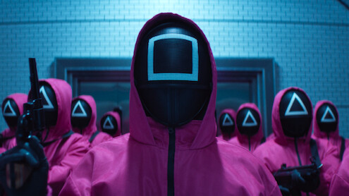 A group of people in pink hooded jumpsuits and masks gathered in Season 2 of 'Squid Game'