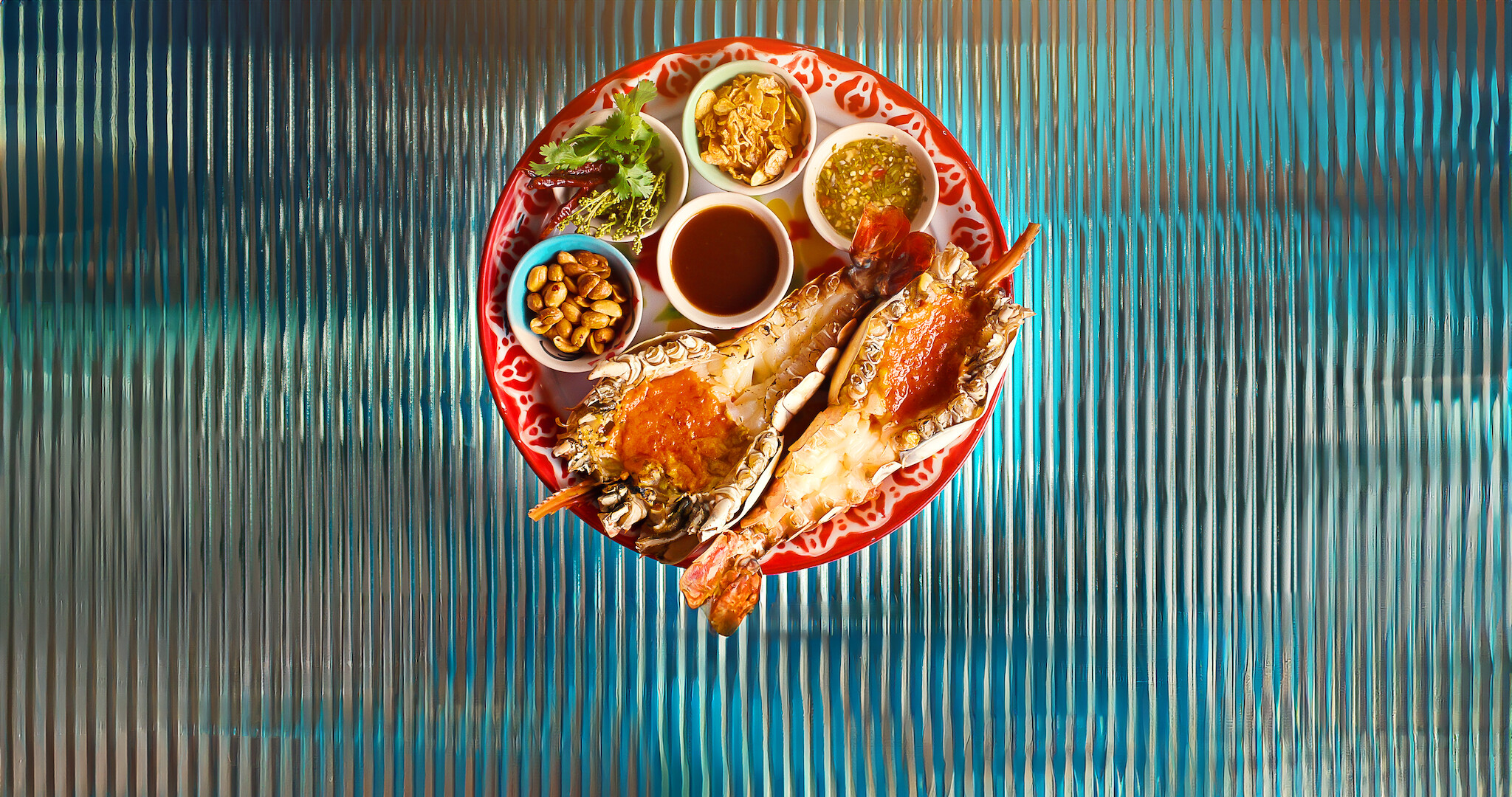 A plate of delicious looking lobster and dipping sauces on top of a glass table