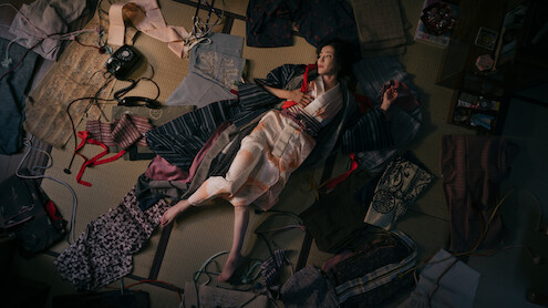 A still image from 'Asura' depicts a woman on the ground surrounded by clothes. 
